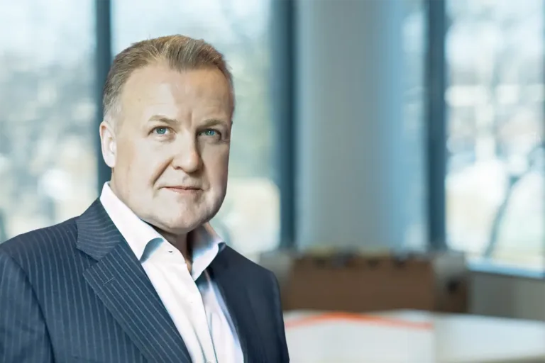 Serious man with slicked-back hair in pinstripe suit and white shirt, office background